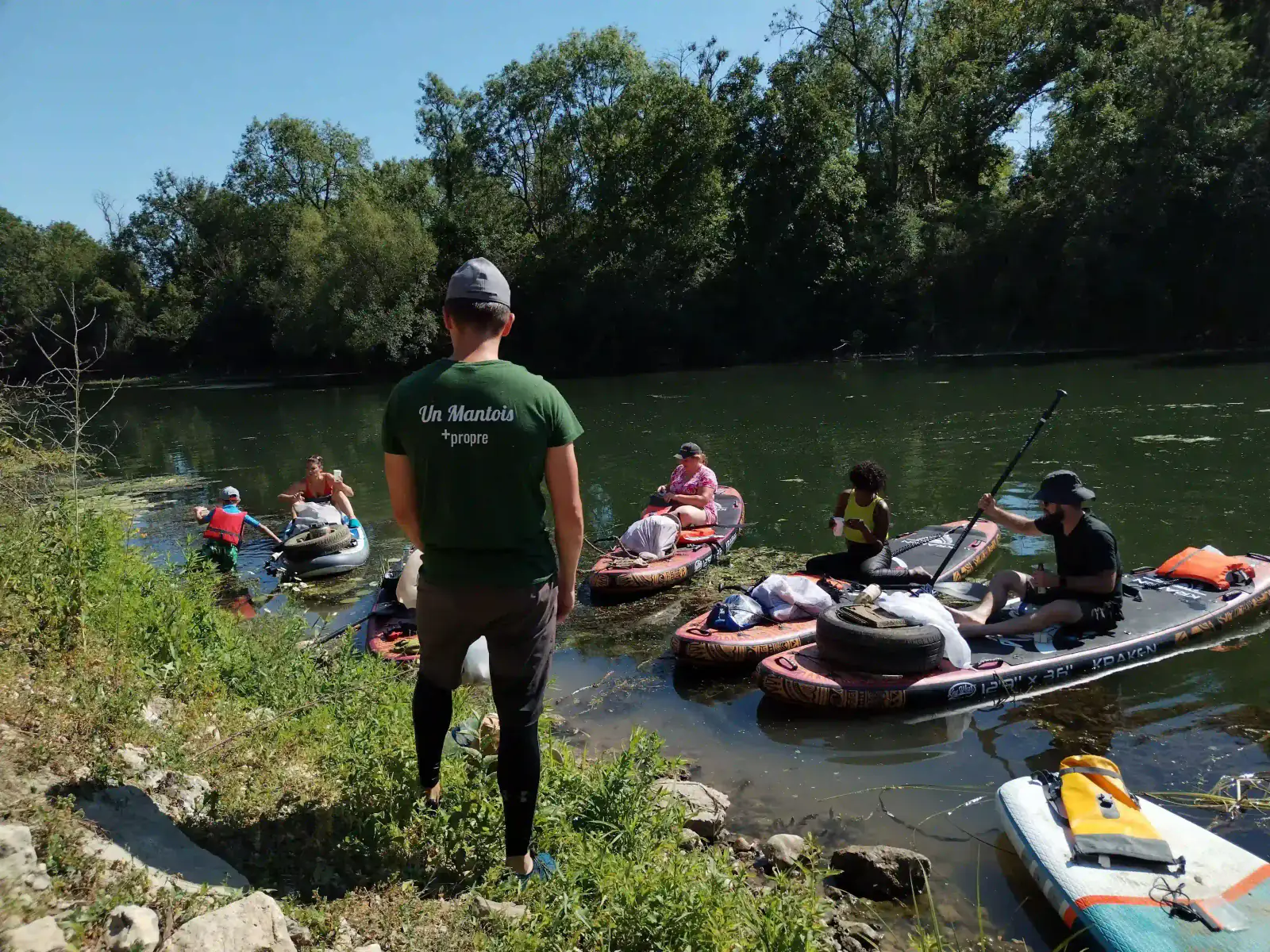 Bénévoles en paddle sur la Seine ramenant pneus et sacs de déchets vers la berge
